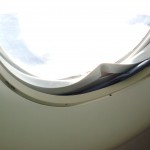My bad karma for being a crabby plane traveler: a messed up window that had seemingly been fixed by a piece of blue cardboard, but which didn't stop it from making a loud rattling noise.