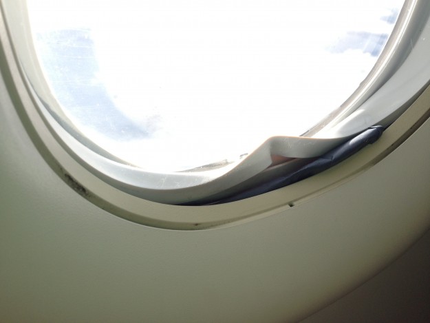 My bad karma for being a crabby plane traveler: a messed up window that had seemingly been fixed by a piece of blue cardboard, but which didn't stop it from making a loud rattling noise.
