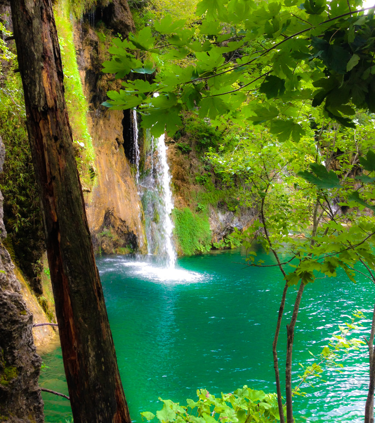 Plitvice Lakes stream of water falling into a teal lake. 