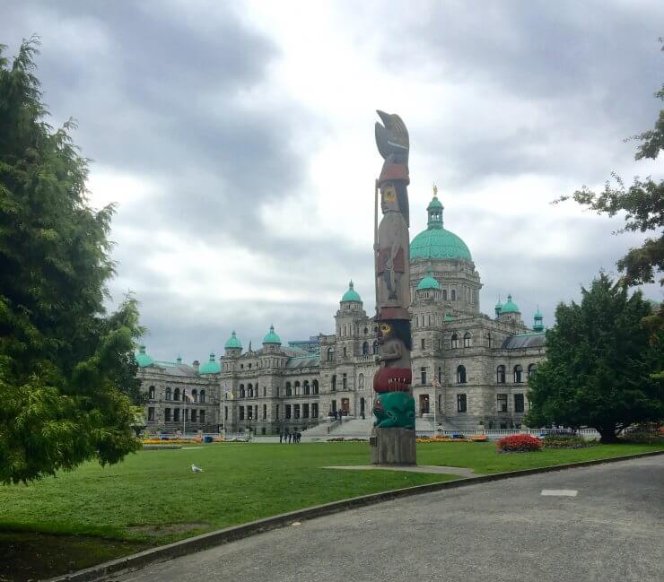 British Columbia Parliament Building with one of the many totem poles in Victoria in front. 