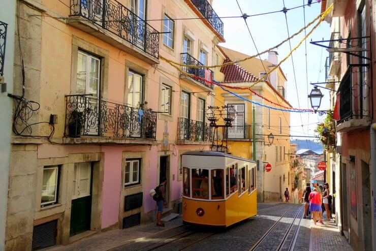 One of Lisbon's Iconic Yellow Trams in the Alfama District with colorful streamers overhead. 