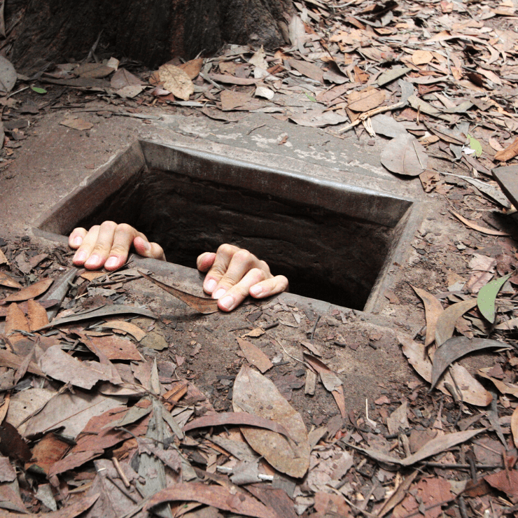 A person coming out of one of the small Cu Chi Tunnels. 