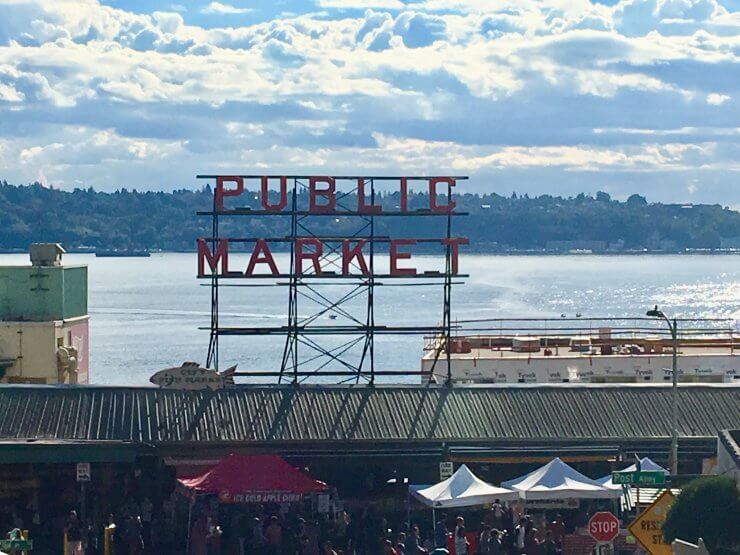 Pike Place Market sign with Elliott Bay behind it. Pike Place Market is a must-see if you have one day in Seattle. 