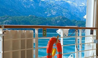 A view of snowcapped mountains in Alaska seen from the deck of a cruise ship. The quickly changing weather patterns in Alaska means you'll want to pack for Alaska with both warm and cold weather clothes for both on the ship and in port.