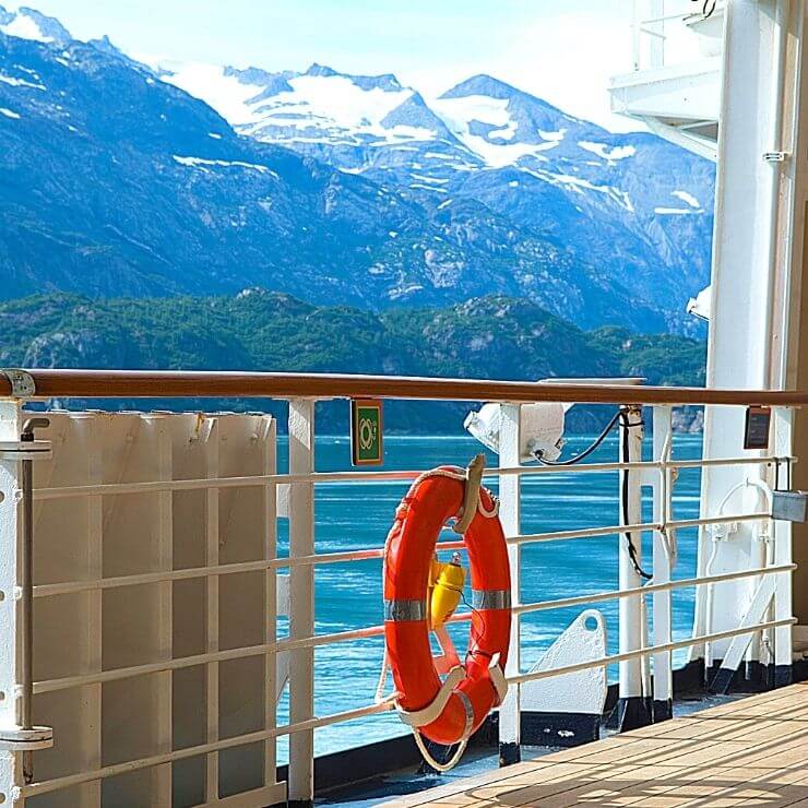 A view of snowcapped mountains in Alaska seen from the deck of a cruise ship. The quickly changing weather patterns in Alaska means you'll want to pack for Alaska with both warm and cold weather clothes for both on the ship and in port.