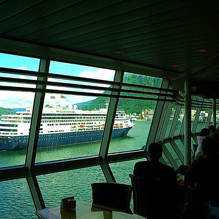 People watching another cruise ship pass by while dining on an Alaska cruise.