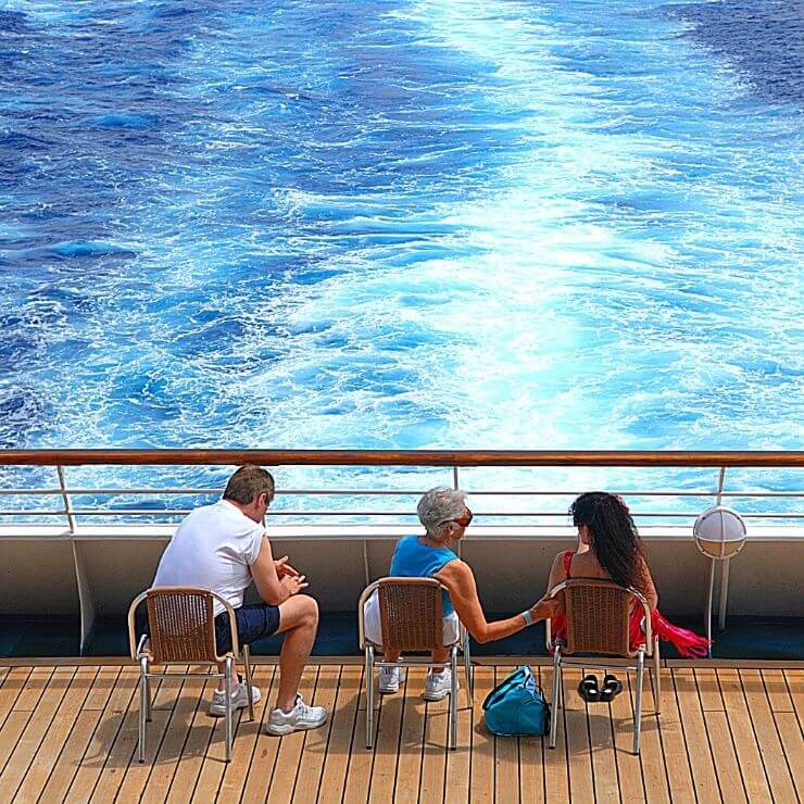 Multigenerational family sitting in chairs on a cruise ship balcony.