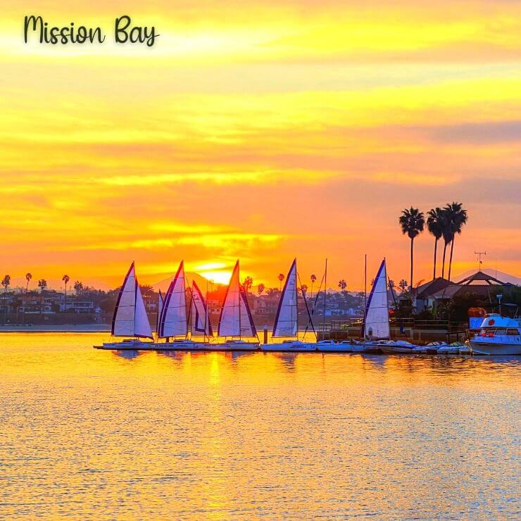 Mission Bay at sunset with sailboats lining the horizon.